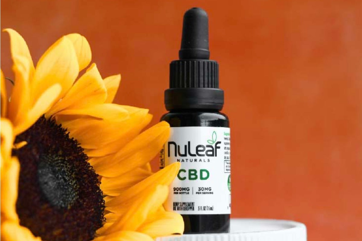 bottle of cbd oil next to a sunflower