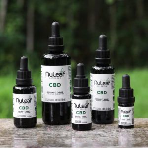 Five CBD oil containers sitting on a smooth surface